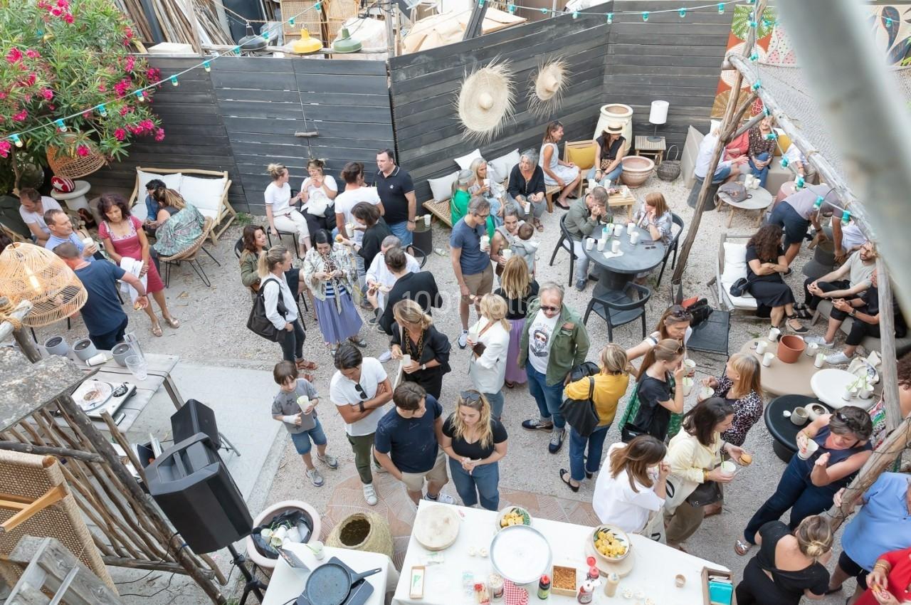 Groupe de personnes rassemblées dans une cour extérieure décorée, discutant et partageant un moment convivial.