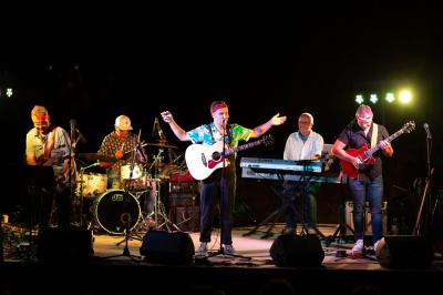 Paysage au crépuscule avec silhouettes de collines, arbres et habitations sous un ciel dégradé du bleu à l'orange.