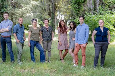 Paysage au crépuscule avec silhouettes de collines, arbres et habitations sous un ciel dégradé du bleu à l'orange.