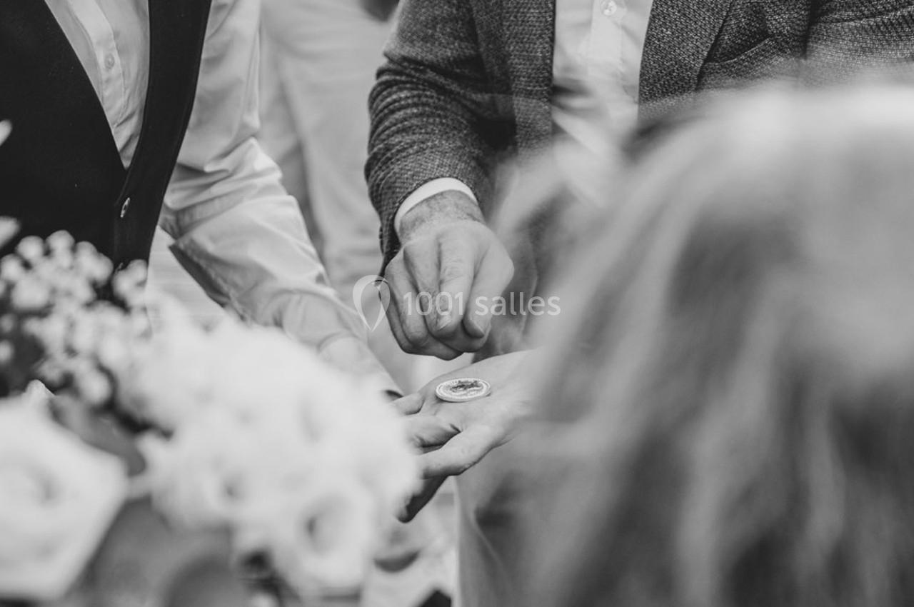 Deux hommes en tenue formelle observent un objet rond tenu dans la main de l'un d'eux, entourés de fleurs.