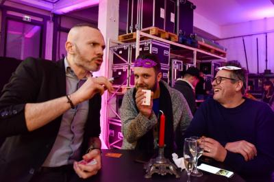 Un groupe de personnes assises et debout, riant et échangeant lors d'un moment convivial en extérieur.