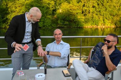 Un groupe de personnes assises et debout, riant et échangeant lors d'un moment convivial en extérieur.
