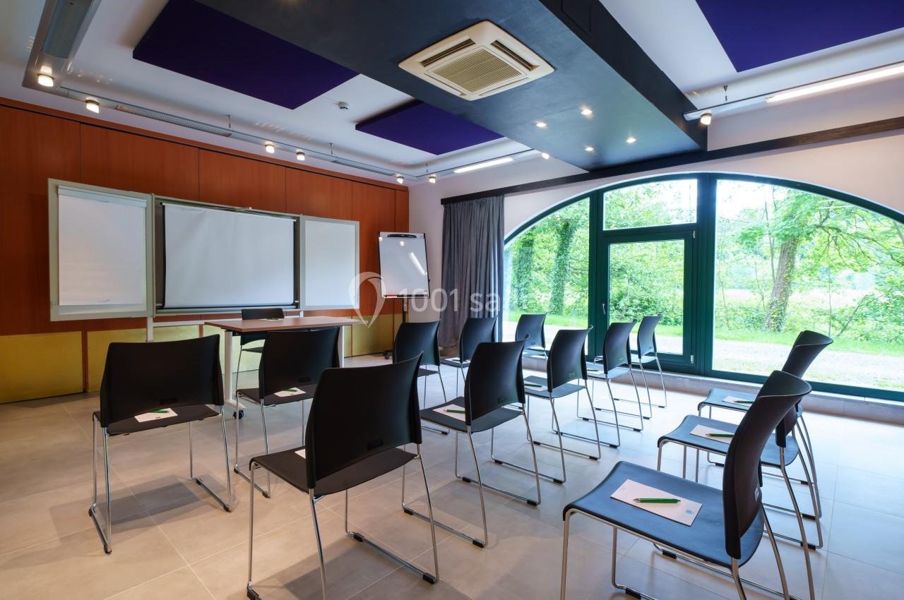 Salle de réunion lumineuse avec chaises disposées face à des tableaux blancs, près d'une grande baie vitrée donnant sur un…