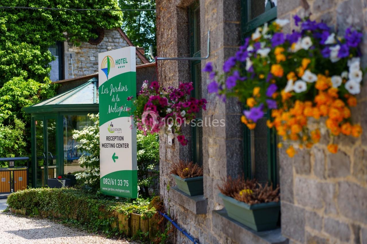 Façade en pierre d'un bâtiment avec des fleurs suspendues et un panneau indiquant un hôtel et un centre de réunion.