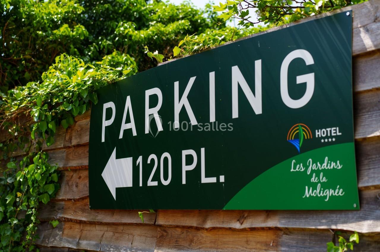 Panneau indiquant un parking de 120 places, avec flèche directionnelle, entouré de végétation.