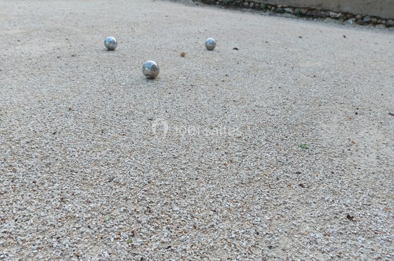 Trois boules de pétanque posées sur un terrain en gravier.