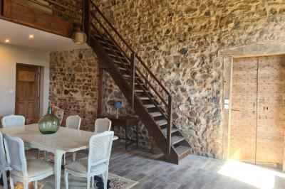 Salon lumineux avec canapé beige, table basse en bois, cuisine ouverte et séparation en bois devant un lit.