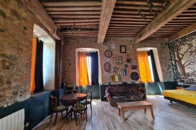 Salon lumineux avec canapé beige, table basse en bois, cuisine ouverte et séparation en bois devant un lit.