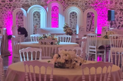 Salon lumineux avec canapé beige, table basse en bois, cuisine ouverte et séparation en bois devant un lit.