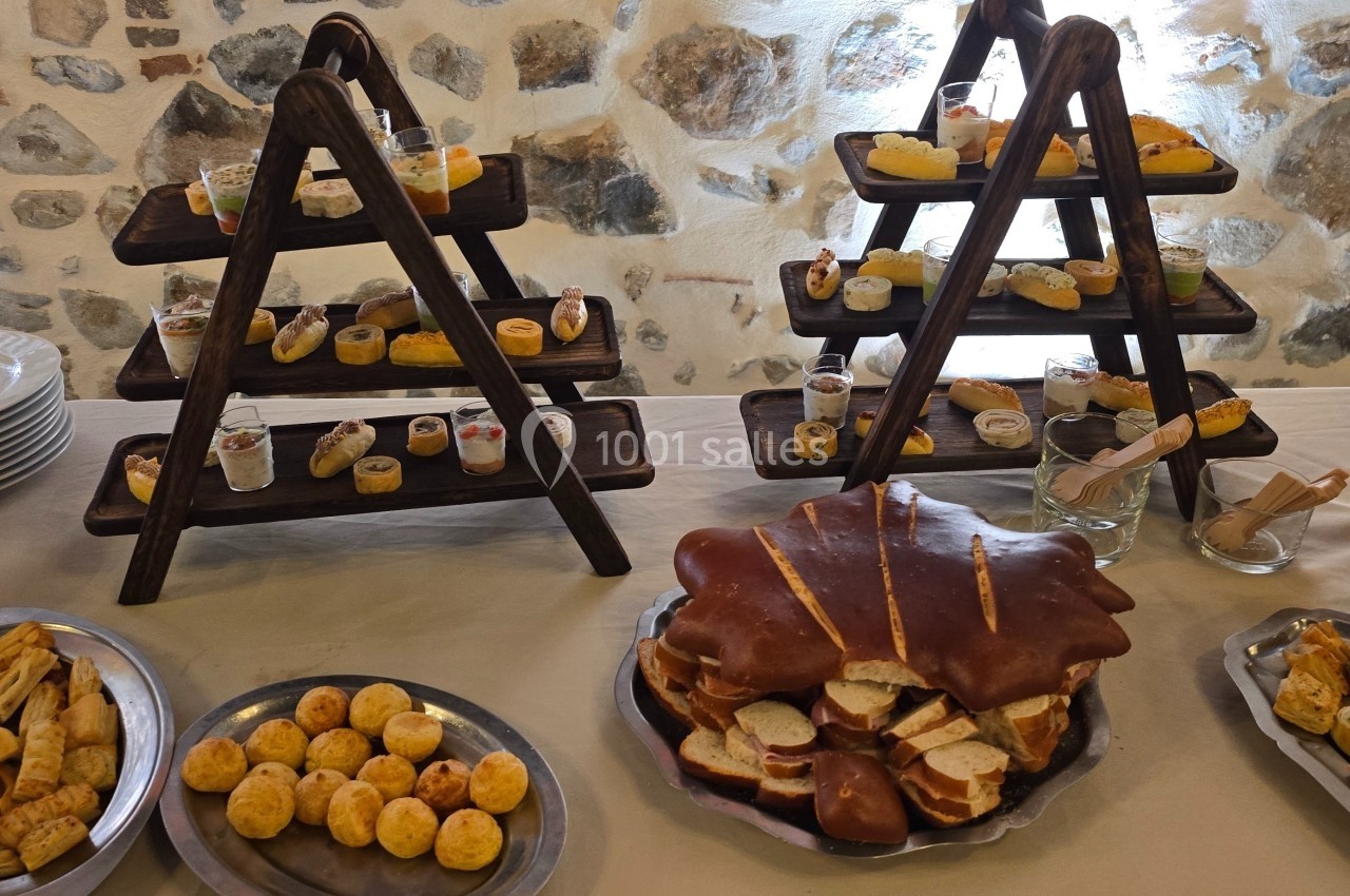 Buffet avec présentoirs en bois garnis de bouchées salées, pains garnis, assiettes de viennoiseries et piles d'assiettes.