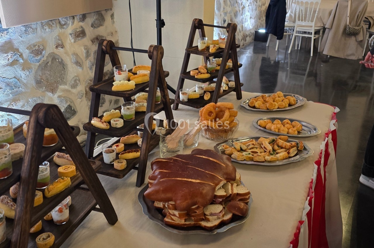 Buffet avec pâtisseries, viennoiseries, verrines et pains disposés sur des présentoirs en bois dans une salle.