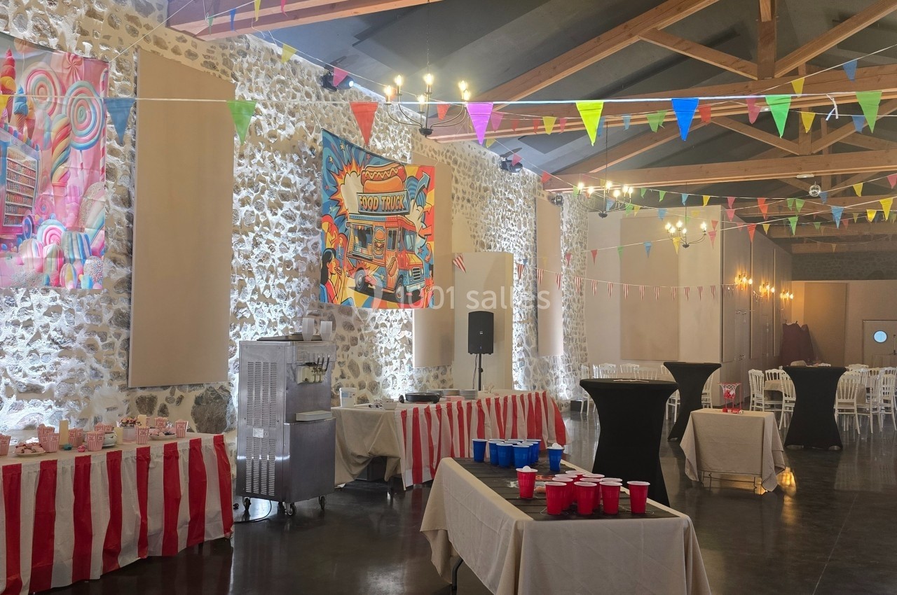 Salle décorée sur le thème de la fête foraine avec guirlandes colorées, affiches et stands à rayures rouges et blanches.