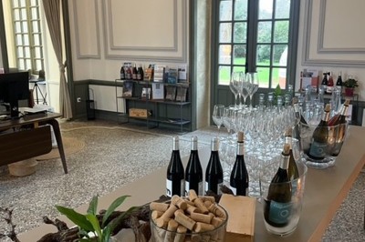 Bâtiment ancien restauré avec façade beige, cour pavée, arbres en arrière-plan et deux personnes au centre.