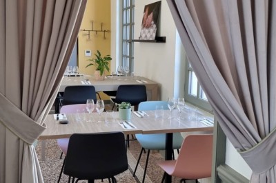 Bâtiment ancien restauré avec façade beige, cour pavée, arbres en arrière-plan et deux personnes au centre.