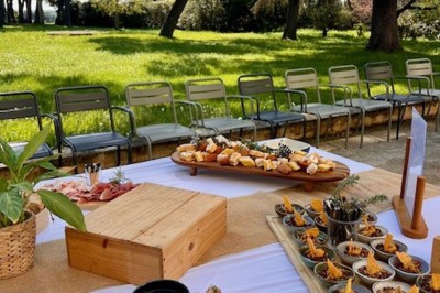 Assiette de brochettes de fruits de mer avec légumes, sauce colorée et riz, servie en extérieur sur une table dressée.
