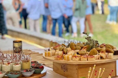 Assiette de brochettes de fruits de mer avec légumes, sauce colorée et riz, servie en extérieur sur une table dressée.