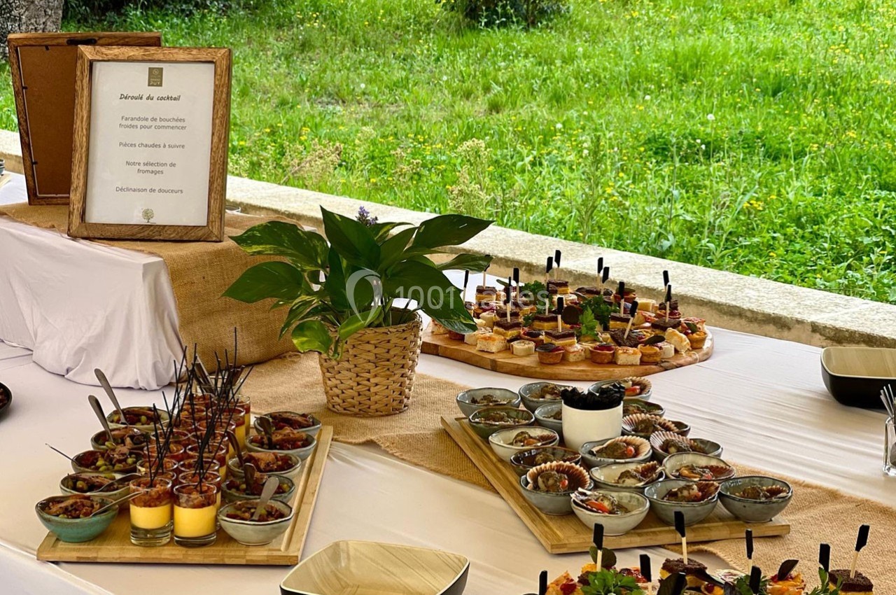 Buffet en plein air avec verrines, plats variés et décorations végétales sur une table blanche.