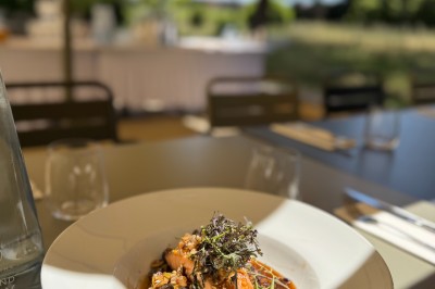 Assiette de brochettes de fruits de mer avec légumes, sauce colorée et riz, servie en extérieur sur une table dressée.