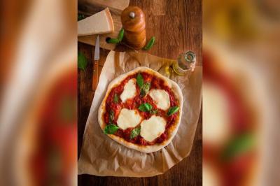 Assiette de charcuterie avec pain plat, cornichons, tapenade, fromage et beurre sur une table en bois.