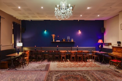 Assiette de charcuterie avec pain plat, cornichons, tapenade, fromage et beurre sur une table en bois.