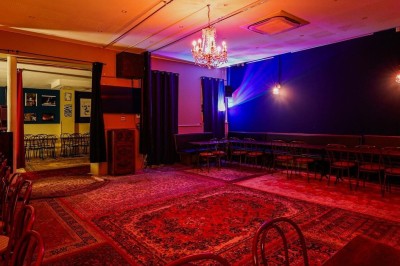 Assiette de charcuterie avec pain plat, cornichons, tapenade, fromage et beurre sur une table en bois.