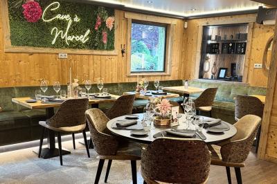 Bain à remous éclairé en violet sous une pergola en bois, avec un sapin décoré et un chalet en arrière-plan.