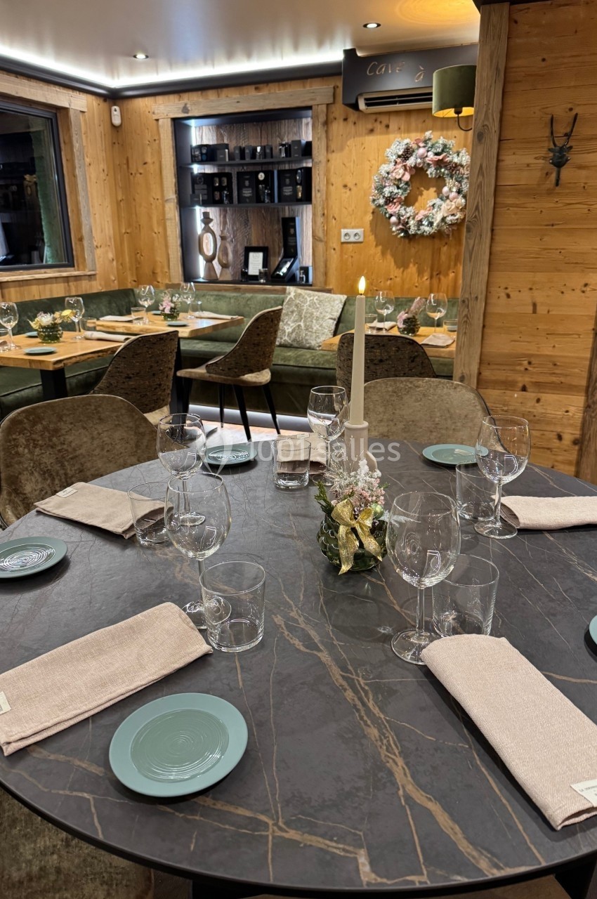 Table élégamment dressée dans un restaurant chaleureux avec décoration en bois, banquettes vertes et couronne murale.