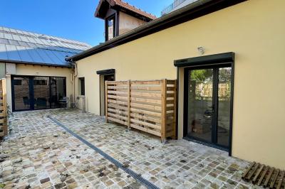 Entrée d'un immeuble avec porte vitrée, numéro 16 et inscription ’Bureaux’, sol pavé avec quelques feuilles.