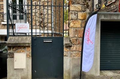 Entrée d'un immeuble avec porte vitrée, numéro 16 et inscription ’Bureaux’, sol pavé avec quelques feuilles.