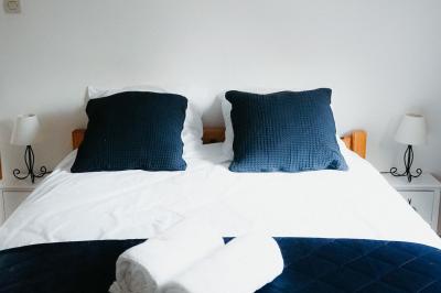 Chambre mansardée avec lit double, serviettes pliées, cygne en serviette, fauteuil et lumière naturelle.