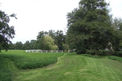 Chambre mansardée avec lit double, serviettes pliées, cygne en serviette, fauteuil et lumière naturelle.