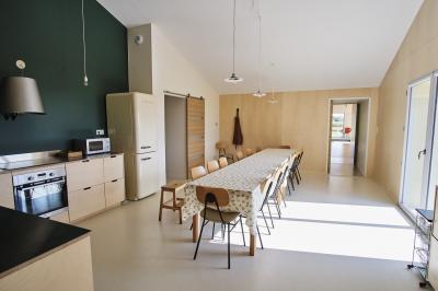 Table décorée avec des bougies, fleurs et sets en osier, entourée de coussins, bancs et éléments rustiques en bois.