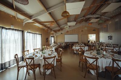 Table décorée avec des bougies, fleurs et sets en osier, entourée de coussins, bancs et éléments rustiques en bois.