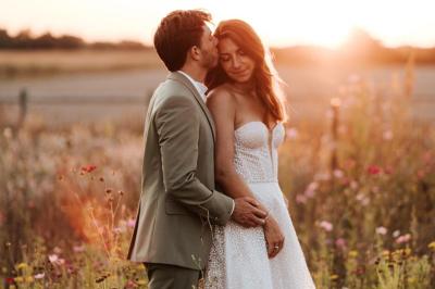 Table décorée avec des bougies, fleurs et sets en osier, entourée de coussins, bancs et éléments rustiques en bois.