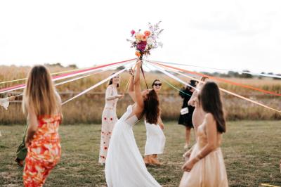 Table décorée avec des bougies, fleurs et sets en osier, entourée de coussins, bancs et éléments rustiques en bois.