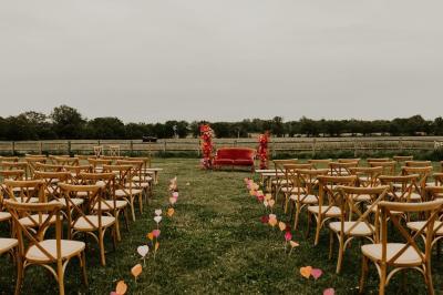 Table décorée avec des bougies, fleurs et sets en osier, entourée de coussins, bancs et éléments rustiques en bois.