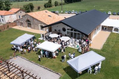 Table décorée avec des bougies, fleurs et sets en osier, entourée de coussins, bancs et éléments rustiques en bois.