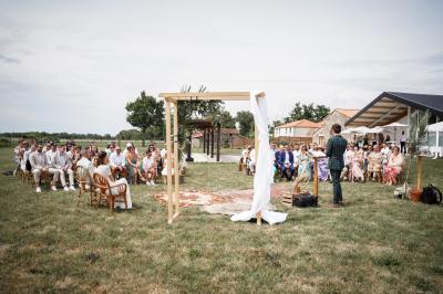 Table décorée avec des bougies, fleurs et sets en osier, entourée de coussins, bancs et éléments rustiques en bois.
