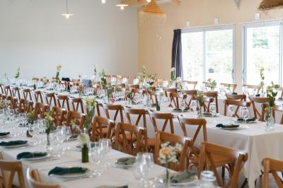 Table décorée avec des bougies, fleurs et sets en osier, entourée de coussins, bancs et éléments rustiques en bois.