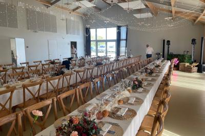 Table décorée avec des bougies, fleurs et sets en osier, entourée de coussins, bancs et éléments rustiques en bois.