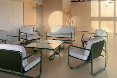 Table décorée avec des bougies, fleurs et sets en osier, entourée de coussins, bancs et éléments rustiques en bois.