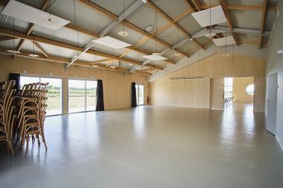 Des personnes participent à un atelier créatif dans une salle lumineuse, entourées de tables et de matériel artistique.