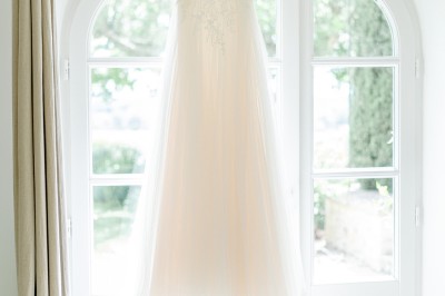 Un couple en tenue de mariage marche dans un champ verdoyant par une journée ensoleillée.