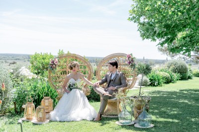 Un couple en tenue de mariage marche dans un champ verdoyant par une journée ensoleillée.