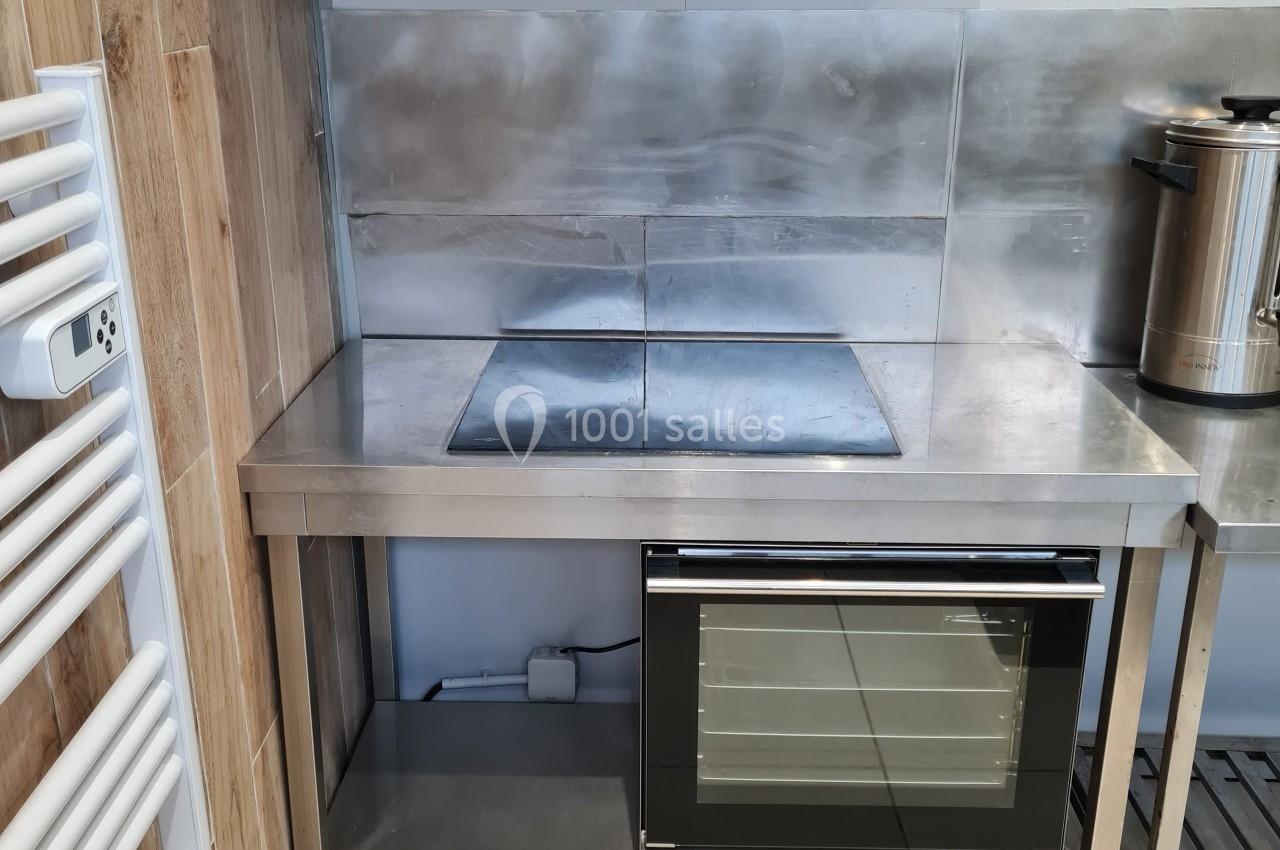 Cuisine équipée avec un four encastré, une plaque de cuisson et une hotte en acier inoxydable sur un plan de travail.