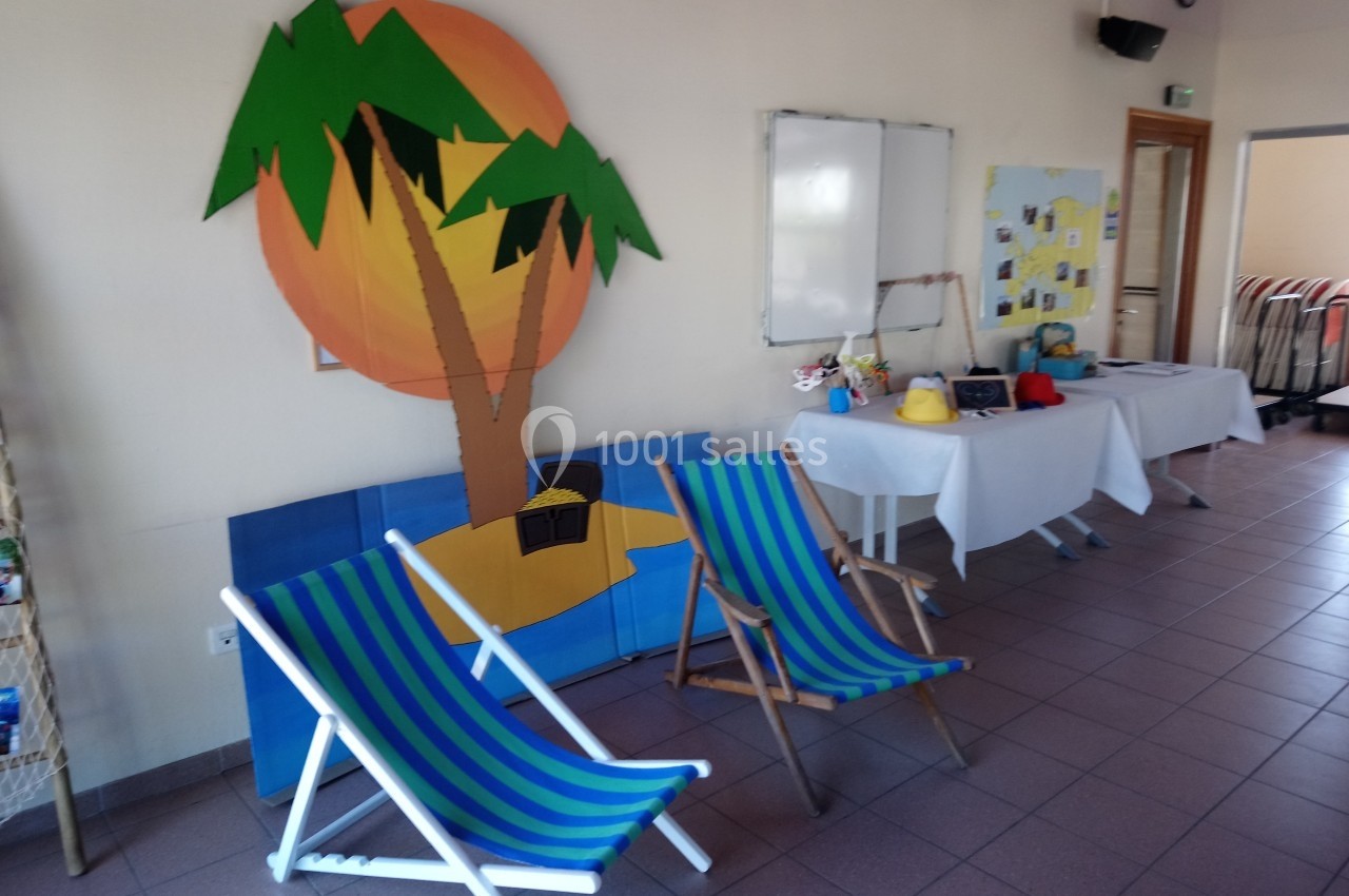 Deux chaises longues colorées devant une décoration murale représentant une plage avec un palmier.