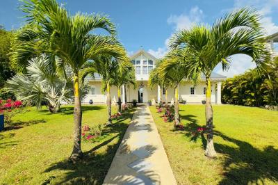 Piscine extérieure entourée de plantes fleuries, statues décoratives et vue dégagée sur un paysage tropical.