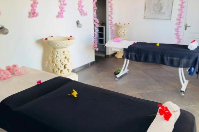 Piscine extérieure entourée de plantes en pot, avec vue sur un paysage tropical et un ciel dégagé.