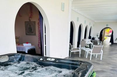 Piscine extérieure entourée de plantes en pot, avec vue sur un paysage tropical et un ciel dégagé.