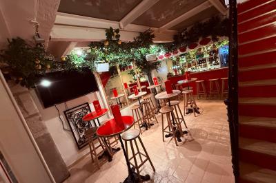 Façade d'un restaurant à l'éclairage rouge vif, avec une entrée ouverte et des décorations florales au-dessus.